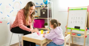 Play therapy session showing therapist and child working together with educational toys and activities in therapeutic playroom setting