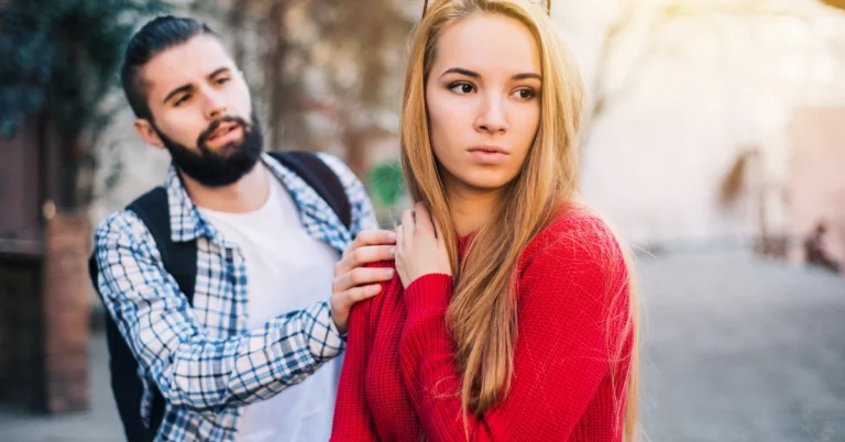 Young woman looking away while her partner reaches out, showing tension and emotional disconnect in a relationship.