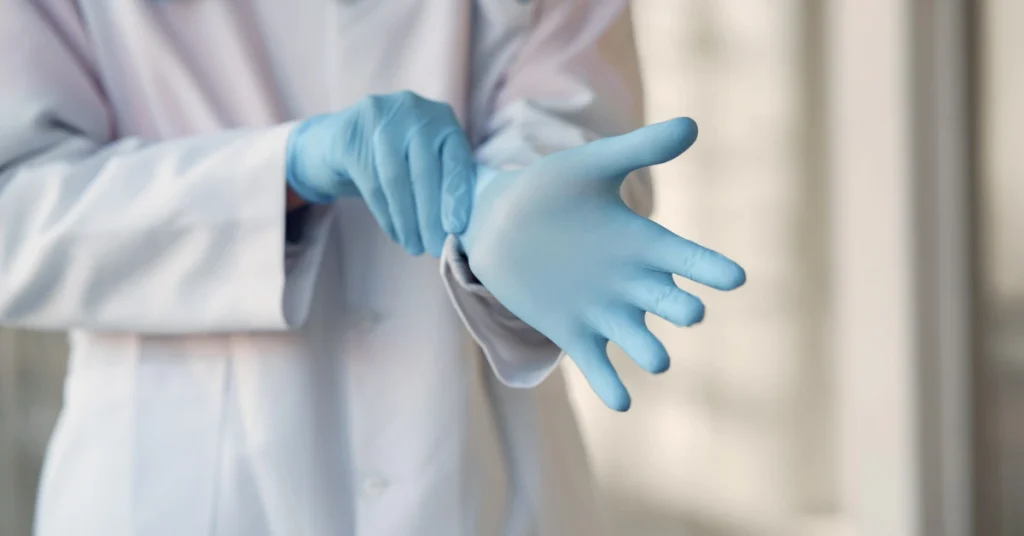 Close-up of a healthcare provider putting on blue protective gloves to ensure safety and cleanliness before a clinical procedure